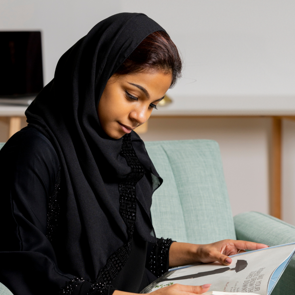 Jeune femme musulmane, voilée qui lit un livre.